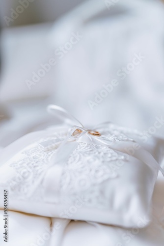 Φωτογραφία Vertical shot of gold wedding rings on a white lacy ring bearer pillow