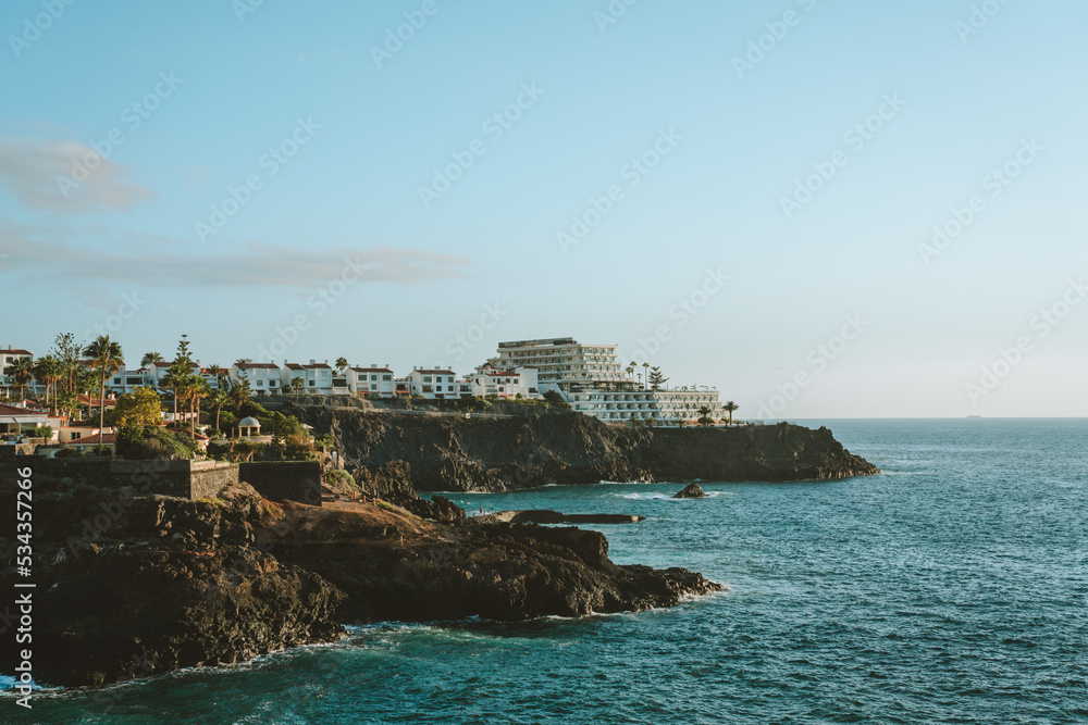 Houses and hotels in a rocky bay with late afternoon light in Tenerife, Spain