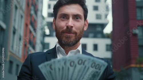 Rich successful businessman hold income salary dollars in hands boast wealthy win cash prize lot of banknotes enjoy profitable business deal satisfied owner look at camera suggest financial exchange