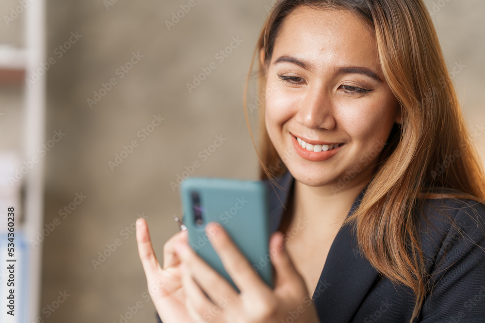 Young pretty asian stock manager checking list of product and working at workstation, using mobile phone. Young pretty asian stock manager checking list of product and working at workstation, using mobile phone.