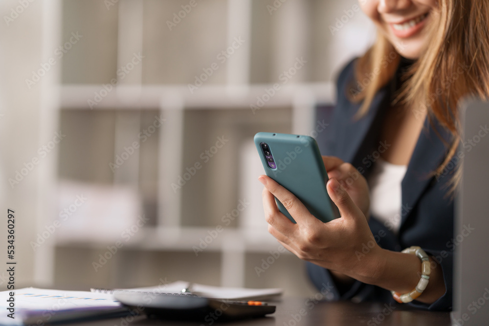 Young pretty asian stock manager checking list of product and working at workstation, texting mobile. Young pretty asian stock manager checking list of product and working at workstation, texting mobile.
