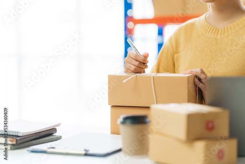 Young pretty asian entrepreneur warehouse worker working and checking product inventory in warehouse showroom.