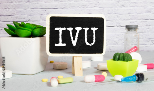 IVU. text on white paper, gray background, near pills and stethoscope in blue. photo