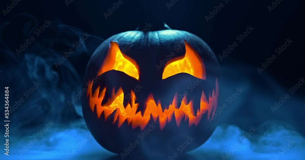 Spooky Halloween jack o lantern with glowing scary face carved out of a ...