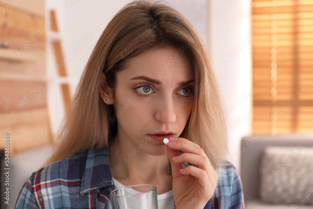 Upset young woman taking abortion pill at home Upset young woman taking abortion pill at home