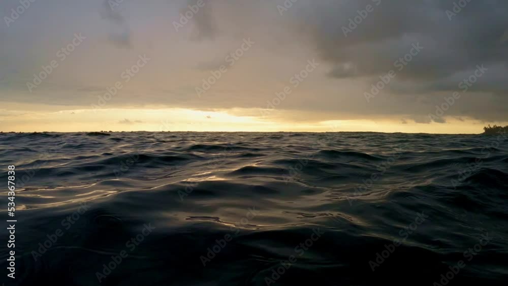 Floating in the pacific ocean off the coast of Hawaii at sunset in slow motion 