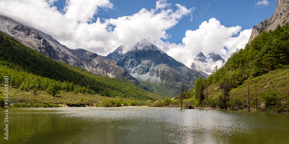 Beautiful scene in the Daocheng Yading National Nature Reserve, Ganzi, Sichuan, China. The Yangmaiyong Snow Mountain (know as “Manjusri” in Tibetan) was covered by cloud, panorama Beautiful scene in the Daocheng Yading National Nature Reserve, Ganzi, Sichuan, China. The Yangmaiyong Snow Mountain (know as “Manjusri” in Tibetan) was covered by cloud, panorama
