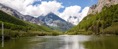 Panorama of the The green meadows, river and snow mountains in Yading and Daocheng, the last Shangri-La, in Sichuan, China, shot in summer time.