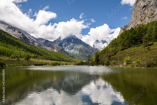 Horizontal image of the mountains reflection through the beautiful lake in Daocheng Yading, Sichuan, China