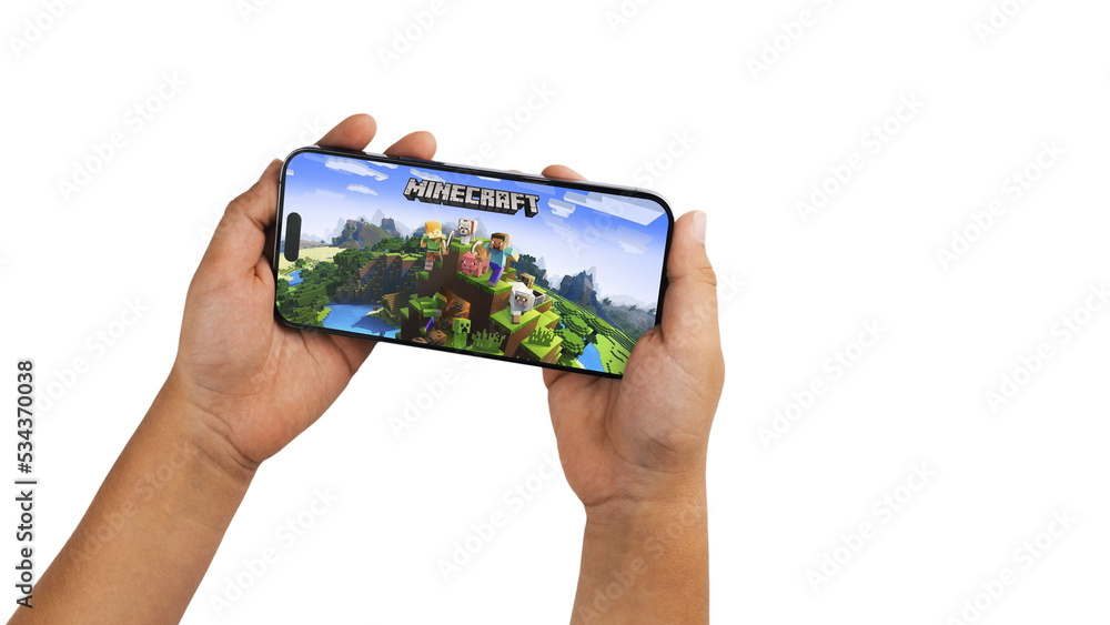 Fototapeta premium Child holding a smartphone iPhone 14 Pro with Minecraft mobile game app on the screen. White background. Rio de Janeiro, RJ, Brazil. September 2022
