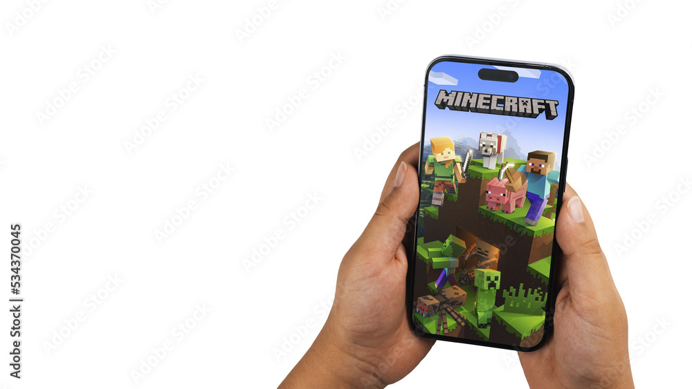 Fototapeta premium Child holding a smartphone iPhone 14 Pro with Minecraft mobile game app on the screen. White background. Rio de Janeiro, RJ, Brazil. September 2022