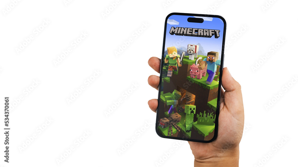 Fototapeta premium Child holding a smartphone iPhone 14 Pro with Minecraft mobile game app on the screen. White background. Rio de Janeiro, RJ, Brazil. September 2022