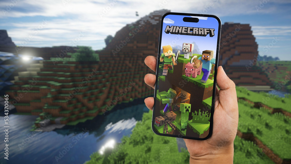Fototapeta premium Child holding a smartphone iPhone 14 Pro with Minecraft mobile game app on the screen. Website blurred on background. Rio de Janeiro, RJ, Brazil. September 2022