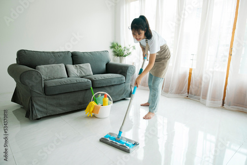 Young woman cleaning floor using mop at home.