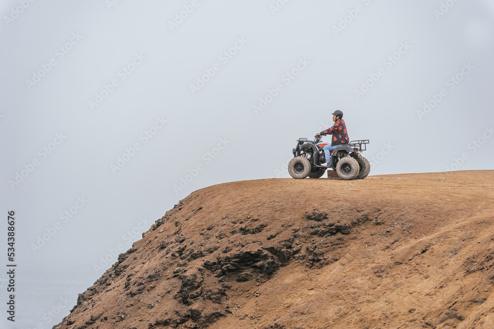 Person driving a quad bike over a hill overlooking the landscape