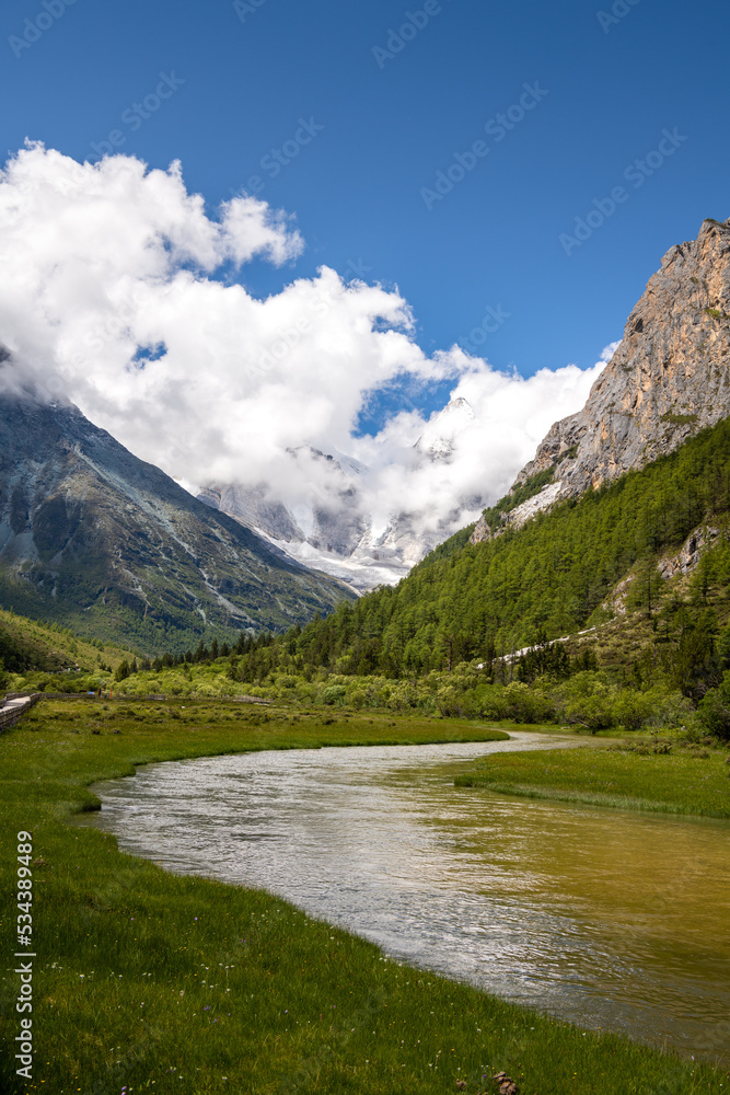 S-shape river and mountains covered with clouds. The scenic spot is located in Daocheng Yading, Sichuan, China. Vertical image with copy space for text