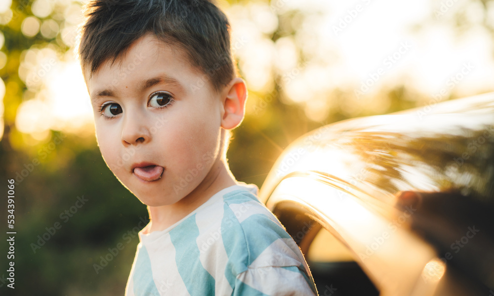 Happy funny little boy, traveling by car enjoying weekend trip with family, sticking his head out of the window car. Facial expression. Funny little boy Happy funny little boy, traveling by car enjoying weekend trip with family, sticking his head out of the window car. Facial expression. Funny little boy