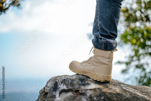 Leg in jeans wearing trekking sneakers on the mountain