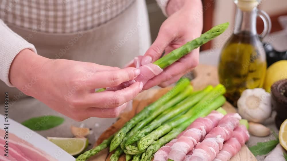 Woman Cooking asparagus wrapped with bacon at domestic kitchen Woman Cooking asparagus wrapped with bacon at domestic kitchen