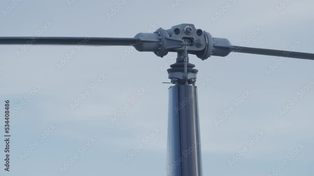 Close up slow motion rotors turning on R22 helicopter against cloudy sky Close up slow motion rotors turning on R22 helicopter against cloudy sky