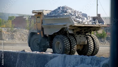 The dump truck backs up and pours the stone into the bunker. Back view