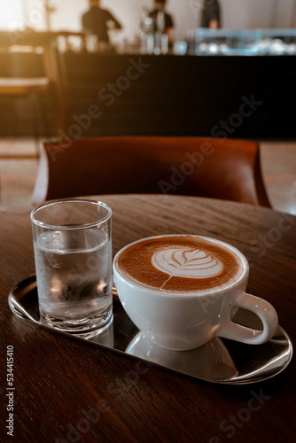 Hot coffee latte with latte art milk foam in cup mug on wood desk on top view. As breakfast In a coffee shop at the cafe,during business work concept