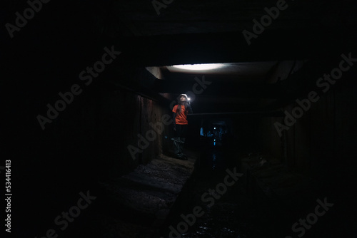 Female digger with flashlight explores the tunnel