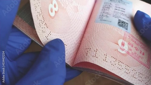 Close-up of a customs officer's hands, checking a Russian passport with stamps and visas of different countries. The concept of travel.