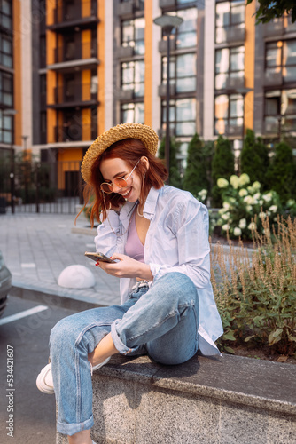 Young lady sitting stairs typing device outside urban city street