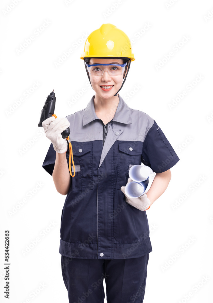 A female worker in a hard hat and uniform carrying tools