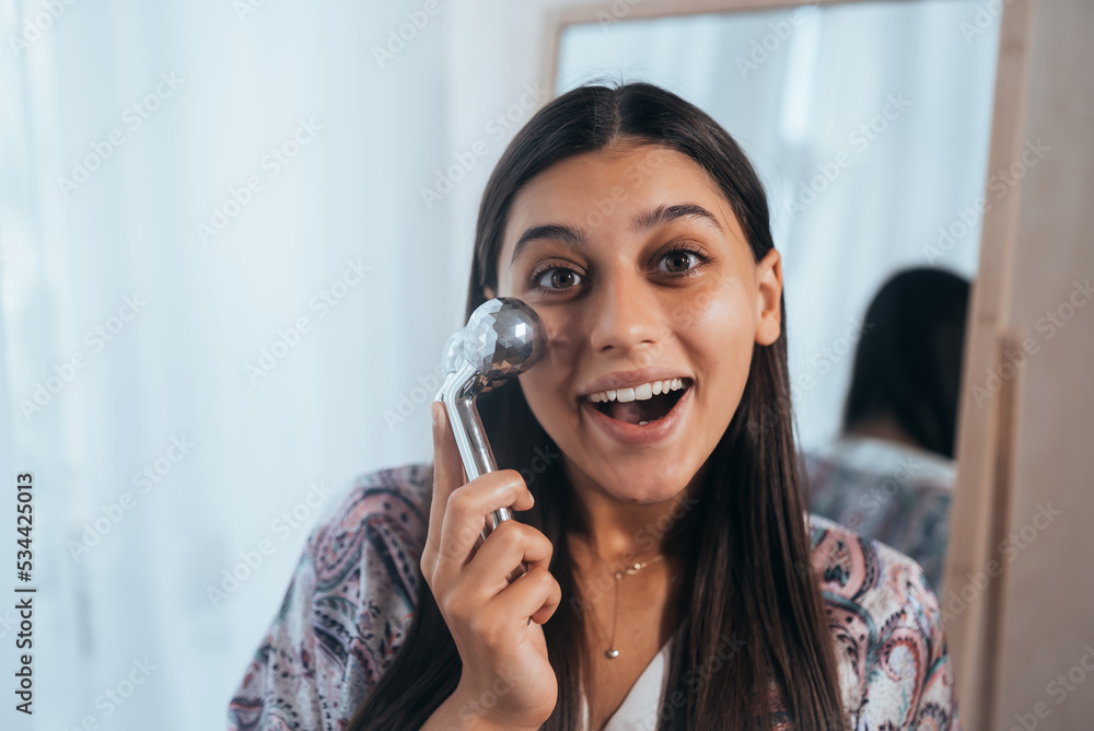 Woman massaging her cheek with massage Y-shaped ball roller. Woman massaging her cheek with massage Y-shaped ball roller.