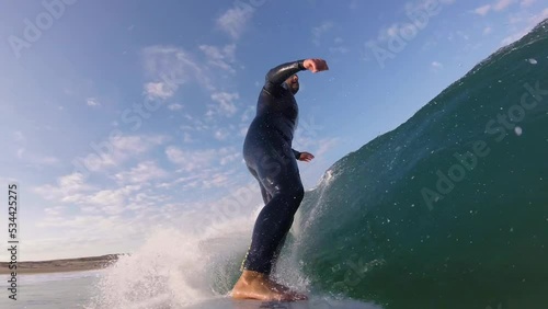 Close up slow motion shot of Handsome guy surfing a green wave in guincho surf spot. strong snap on the end. generating a lot of speed. Guincho, Cascais.