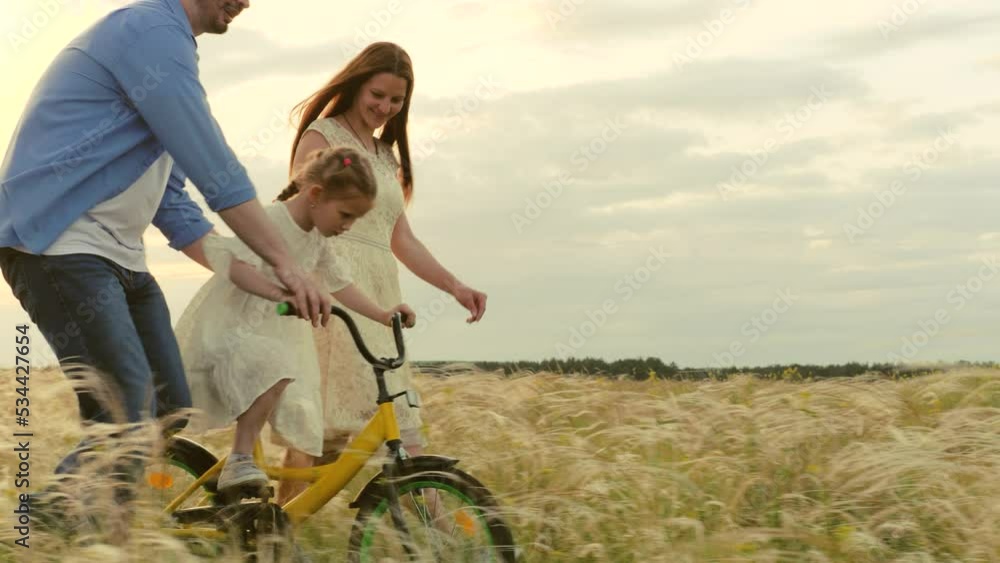 happy parents teach smiling child daughter ride bike. happy family