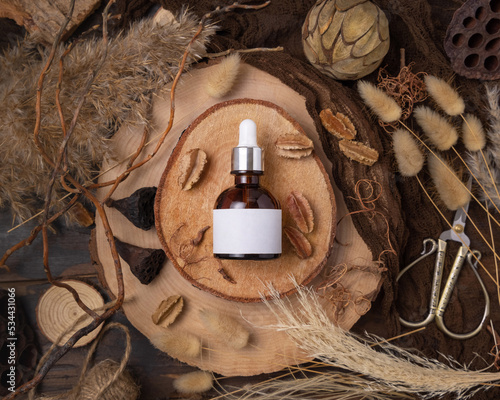 Cosmetic dropper bottle on wood near natural boho decorations top view. Label Mockup