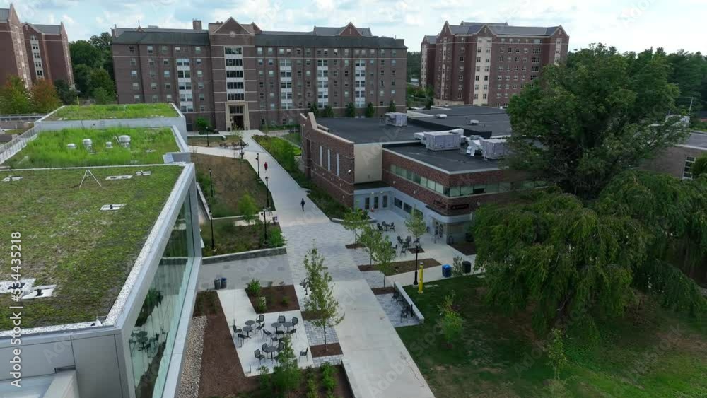 Aerial tilt up shot reveals college dorm building. Academic buildings feature green spaces on roof. Sidewalks make campus walkable for students. Residential university life theme. Aerial tilt up shot reveals college dorm building. Academic buildings feature green spaces on roof. Sidewalks make campus walkable for students. Residential university life theme.