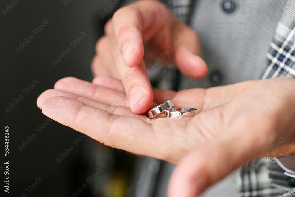 The groom looks at the wedding rings, holding them in his hands. Preparation for the wedding. Wedding celebration.