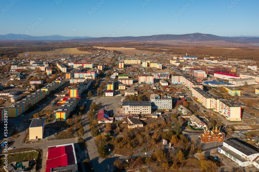 Aerial view of the northern urban-type settlement of Ola. Top view of painted multi-colored buildings. Ola is the administrative center of the Olsky district of the Magadan region. Siberia, Russia.