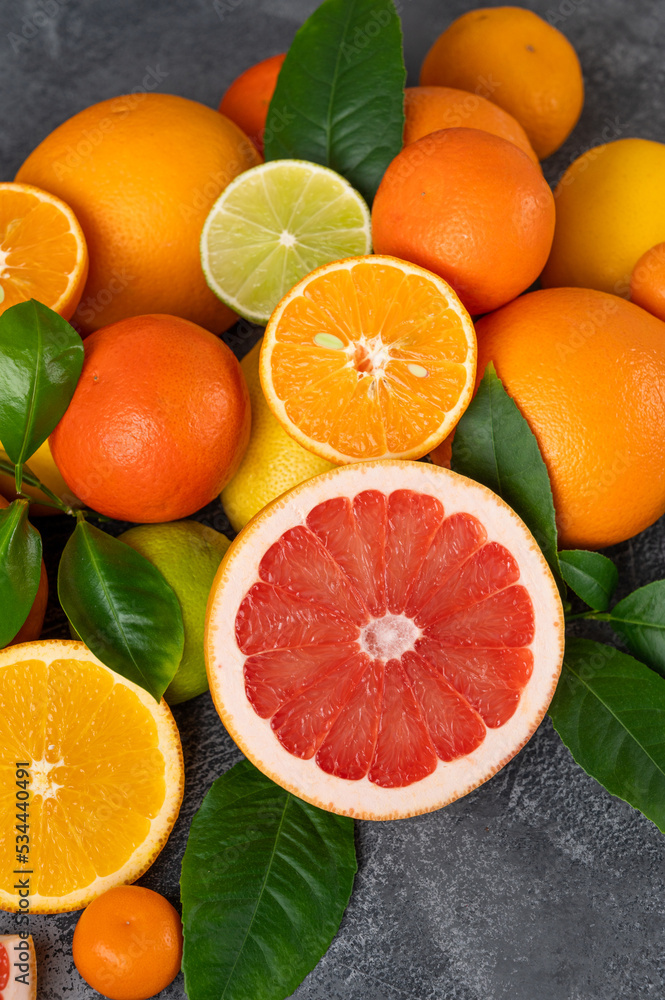 Different citrus fruits with leaves on a concrete background. Healthy food. Top view Different citrus fruits with leaves on a concrete background. Healthy food. Top view