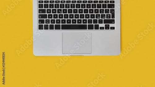 Business woman hands typing on laptop top view over yellow office desk. Working on quarterly reports with coffee cup. Smark working at home. Stopmotion