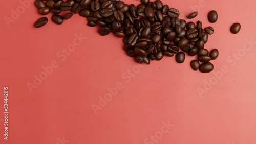Heart made from Roasted Coffee beans blowing out on pink top view