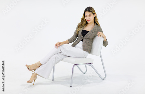 Portrait isolated cutout full body studio shot Millennial Asian successful professional female businesswoman in casual business suit sitting on chair smiling look at camera posing on white background.