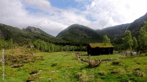 Small cozy outdor shed with grass roof in idyllic valley Leiro in Eidslandet Norway - Timelapse with beautiful clouds and passing shadows from lush green Norway mountain landscape photo