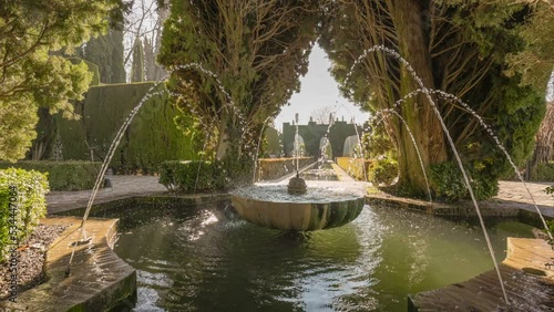 Fountain surrounded by trees in Gardens of the Generalife in Alhambra. Granada, Spain. Camera moves between trees to pond with fountain in Generalife Gardens. Slow motion HDR gimbal shot