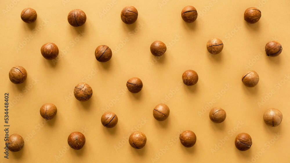 Macadamia nuts pattern. Whole nuts on a brown background