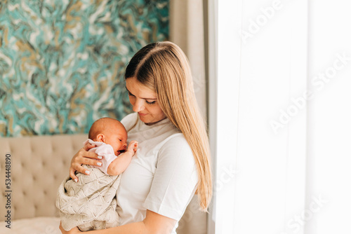 Mom with her baby newborn infant kid child at home take care in the bedroom put on clothes. Woman family women's health and maternity