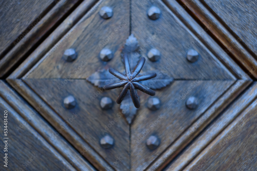 Detail of an old wooden door with traditional metal door knob.