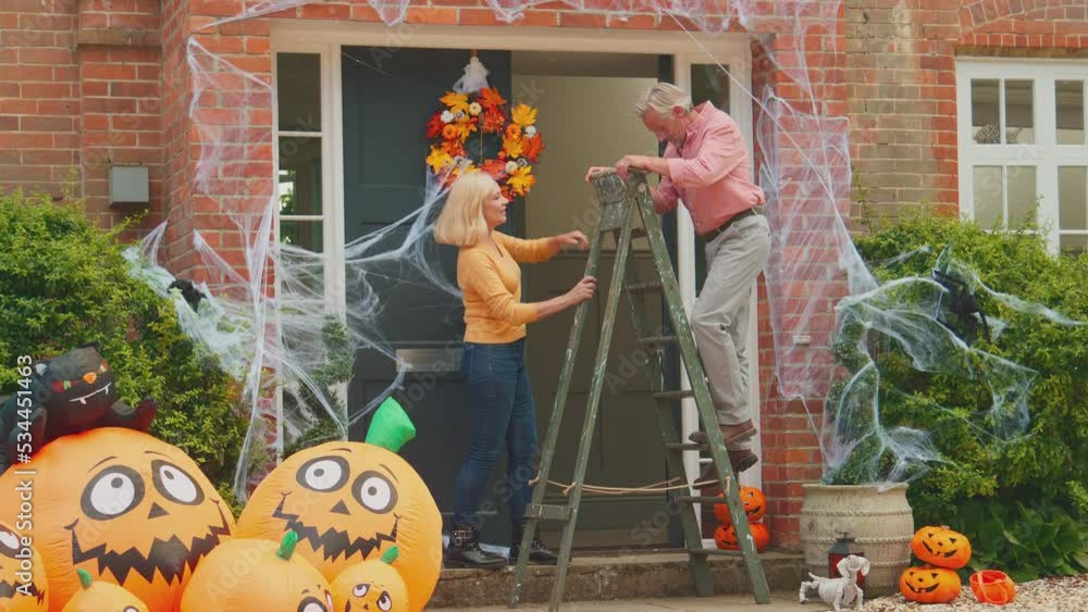 Grandparents with stepladder putting up halloween decorations ready for