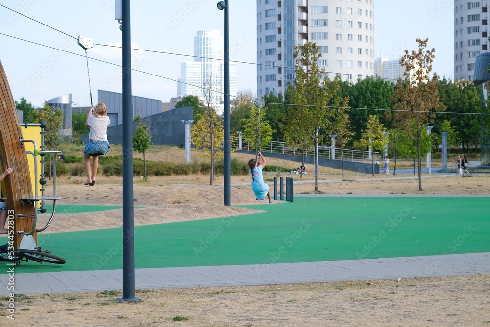 Children ride a zipline on a playground in the city