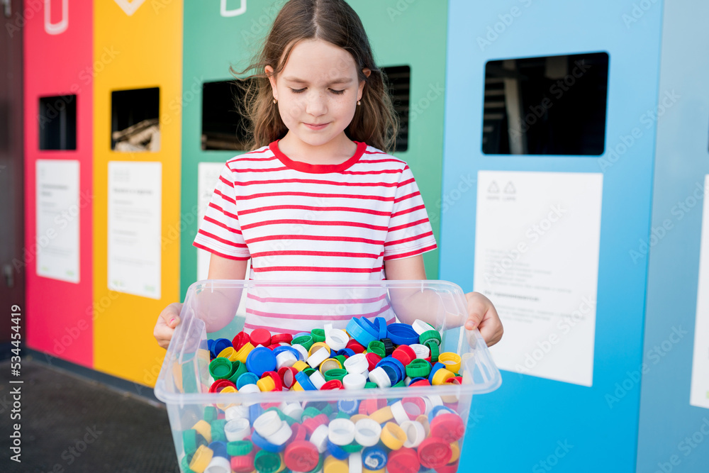 Girls holding container with plastic bottle caps. Kids collecting