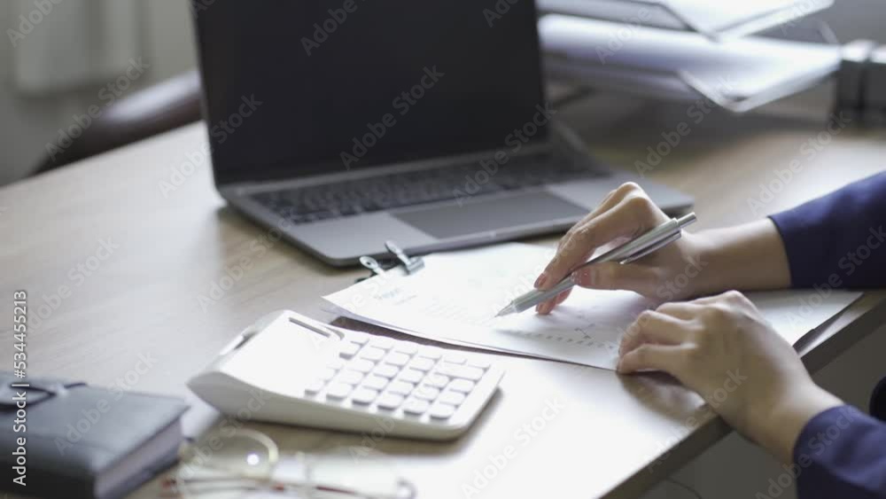 Young Asian businesswoman presses calculator to calculate income tax and corporate income in private office. Finance, accounting, marketer's statistical graph. Young Asian businesswoman presses calculator to calculate income tax and corporate income in private office. Finance, accounting, marketer's statistical graph.